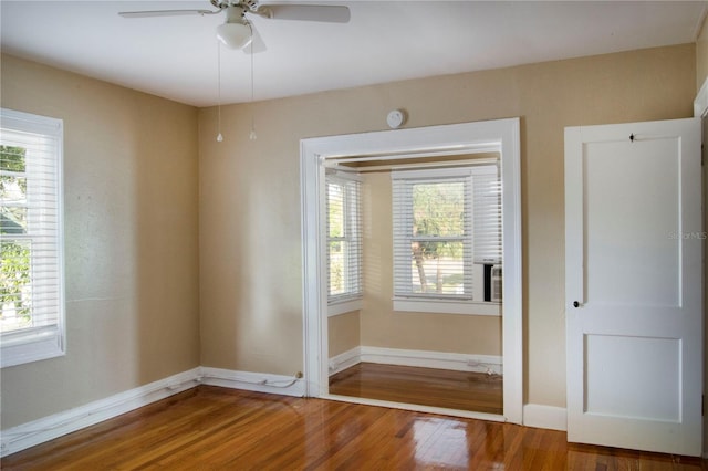 unfurnished room with a healthy amount of sunlight, ceiling fan, baseboards, and wood finished floors