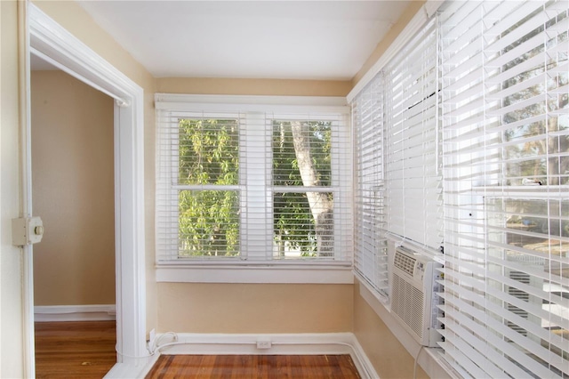 interior space with cooling unit, wood finished floors, and baseboards