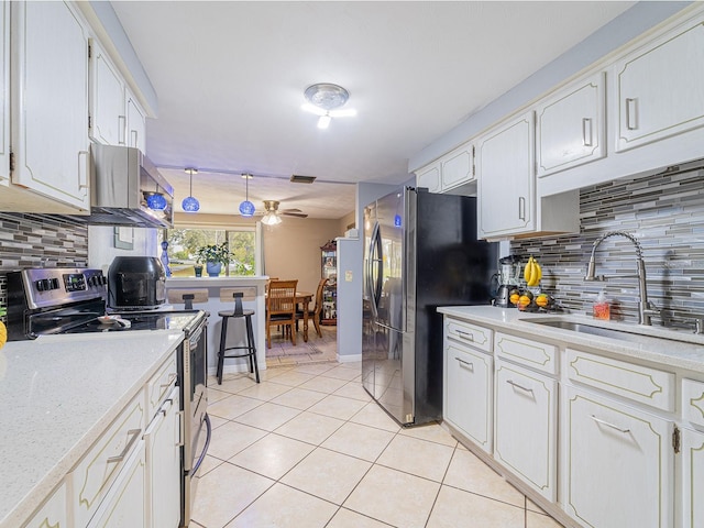 kitchen featuring light countertops, appliances with stainless steel finishes, exhaust hood, light tile patterned flooring, and a sink