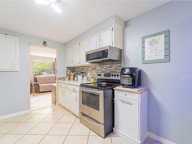 kitchen featuring baseboards, light countertops, light tile patterned floors, decorative backsplash, and appliances with stainless steel finishes