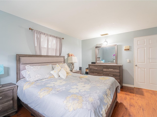 bedroom featuring visible vents, baseboards, and wood finished floors