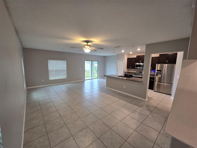 kitchen featuring dark countertops, open floor plan, stainless steel appliances, a sink, and light tile patterned flooring