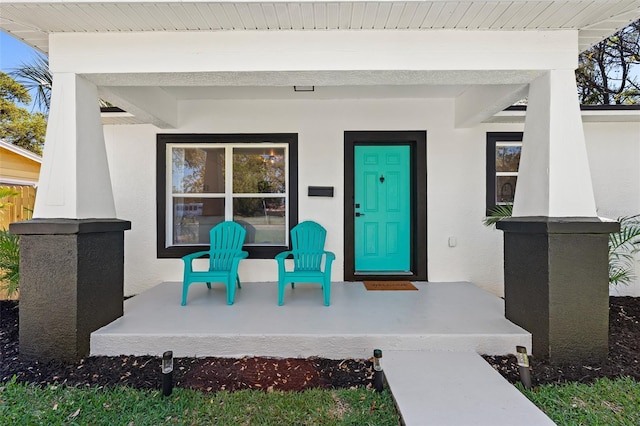 view of exterior entry featuring covered porch and stucco siding