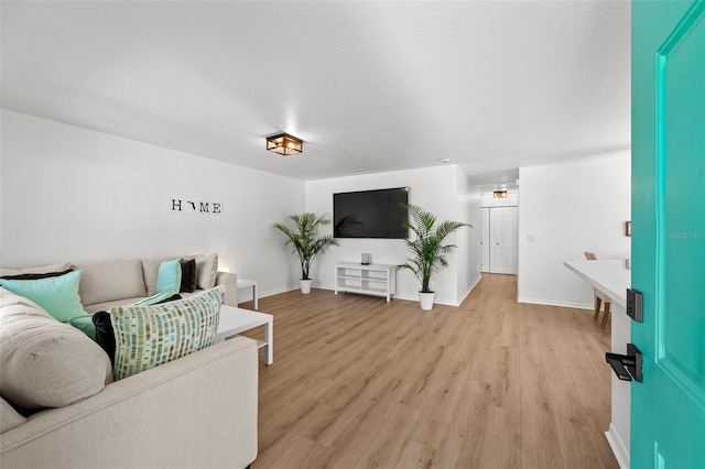 living area featuring light wood-style flooring, baseboards, and a textured ceiling