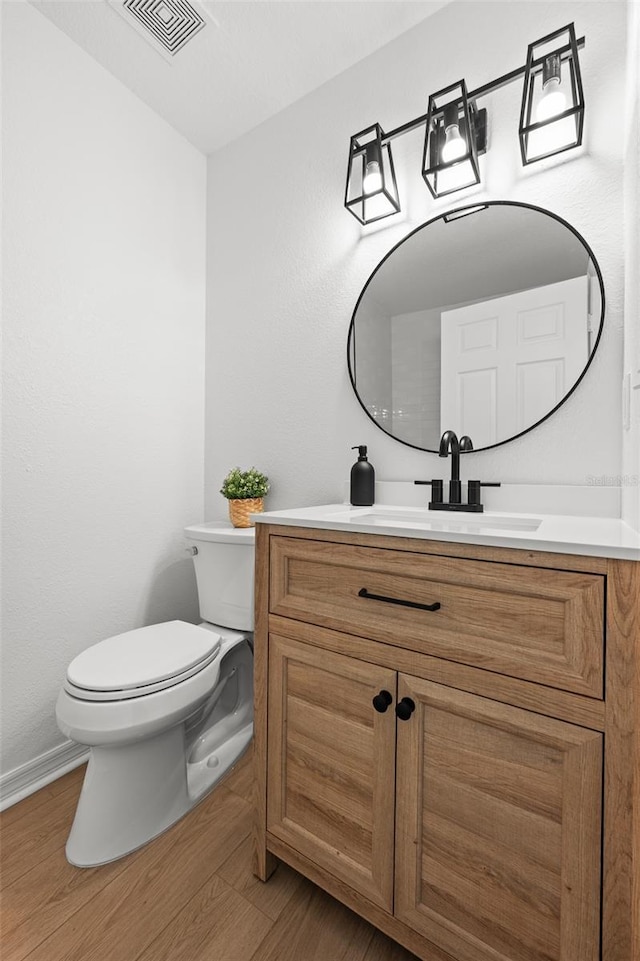 bathroom featuring visible vents, vanity, toilet, and wood finished floors