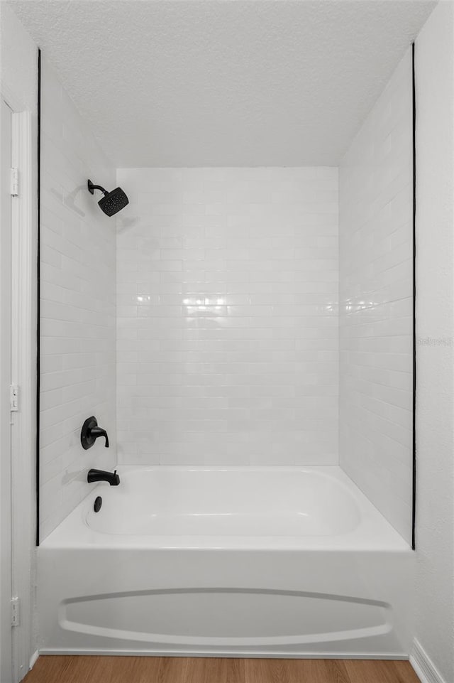 full bath with a textured ceiling, shower / bath combination, and wood finished floors