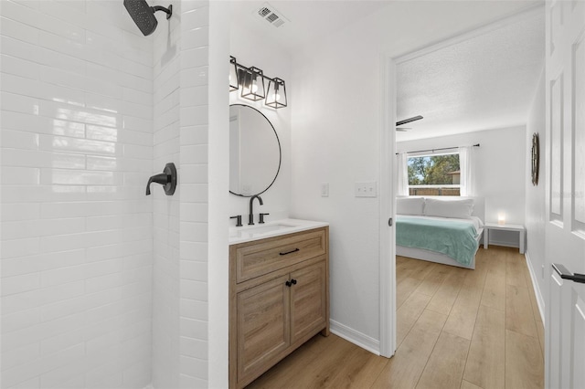 full bath featuring visible vents, connected bathroom, tiled shower, and wood finished floors