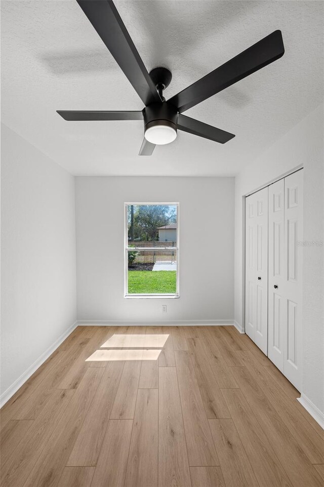 unfurnished bedroom with a textured ceiling, wood finished floors, a ceiling fan, and baseboards