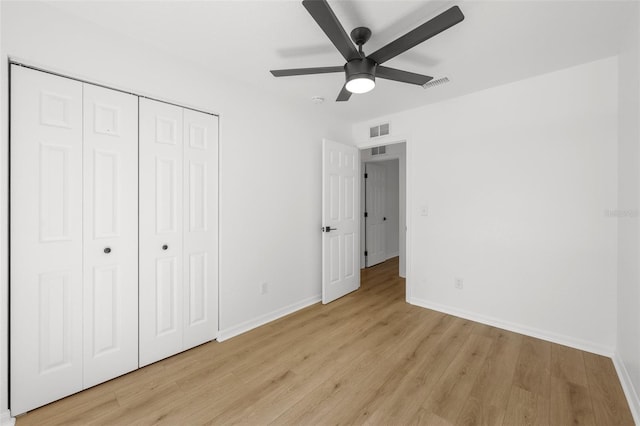 unfurnished bedroom featuring light wood-type flooring, baseboards, visible vents, and a closet