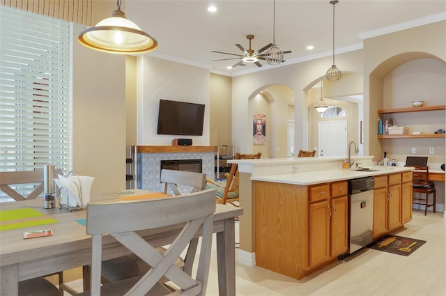 kitchen featuring a fireplace, ornamental molding, open floor plan, a sink, and dishwasher