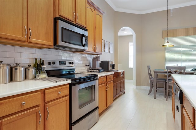 kitchen featuring arched walkways, light countertops, appliances with stainless steel finishes, decorative backsplash, and crown molding