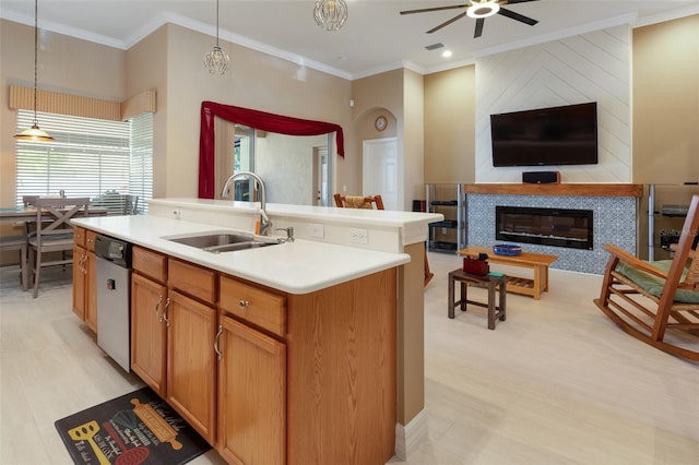 kitchen with a sink, open floor plan, stainless steel dishwasher, ornamental molding, and a tiled fireplace