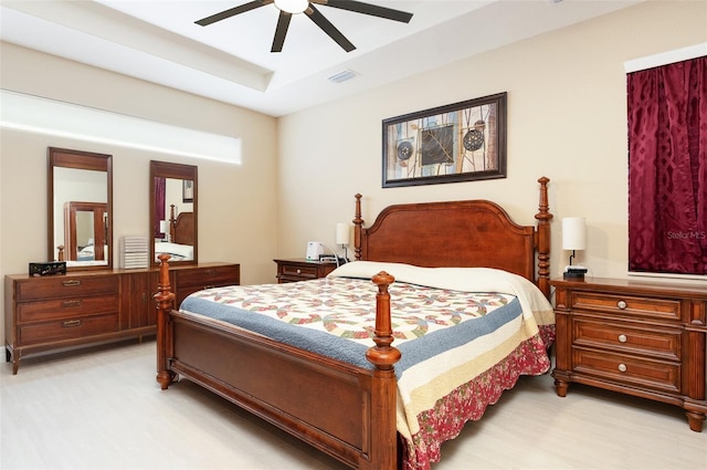 bedroom featuring visible vents, a raised ceiling, and a ceiling fan