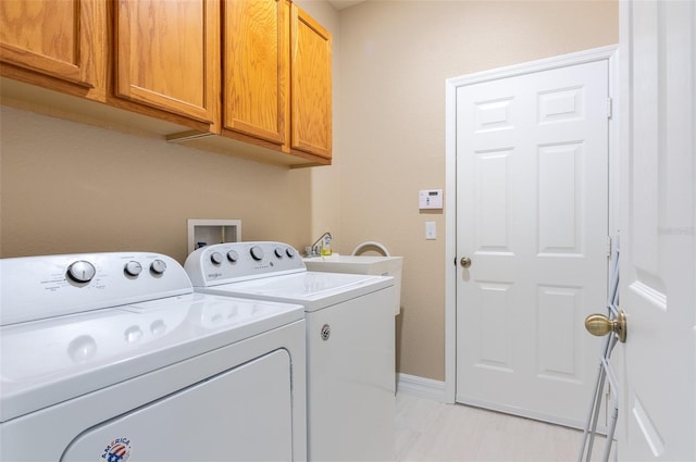 clothes washing area with cabinet space, a sink, washer and clothes dryer, and baseboards