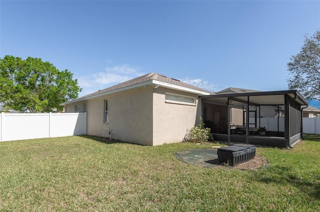 exterior space with a sunroom, stucco siding, fence, and a lawn