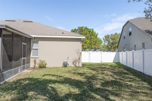 view of yard featuring a sunroom, a fenced backyard, and a gate