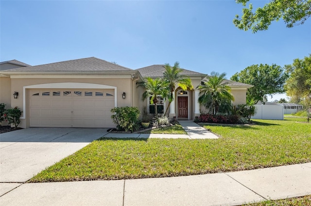 view of front of property with a garage, fence, concrete driveway, stucco siding, and a front lawn