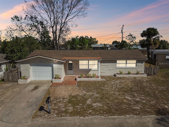 ranch-style house with concrete driveway, fence, and an attached garage