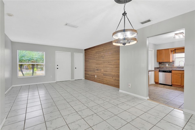 interior space featuring a chandelier, wood walls, visible vents, and a healthy amount of sunlight