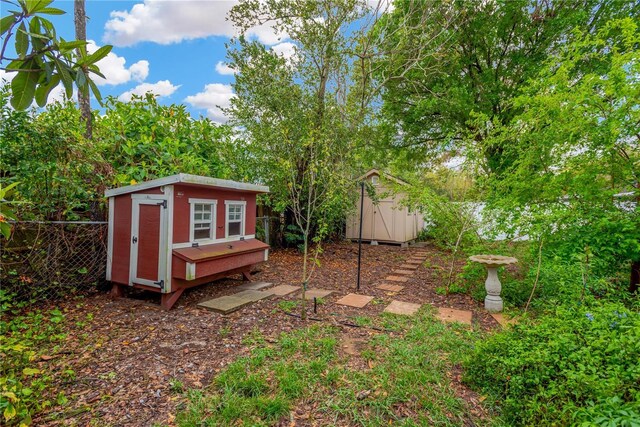 view of yard with fence, a storage unit, and an outdoor structure