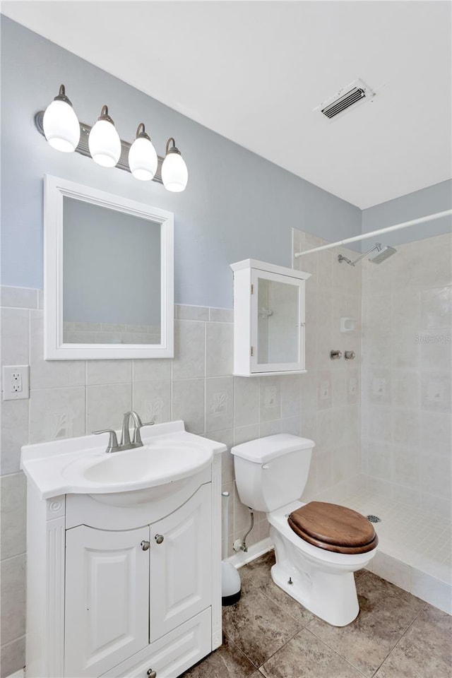 full bath with visible vents, vanity, toilet, and tiled shower