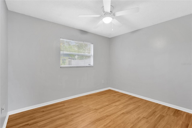 empty room featuring light wood finished floors, baseboards, and a ceiling fan