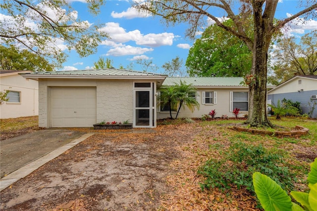 single story home featuring metal roof, an attached garage, and driveway