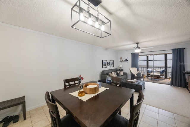 dining room with ceiling fan, a textured ceiling, light tile patterned flooring, light colored carpet, and crown molding