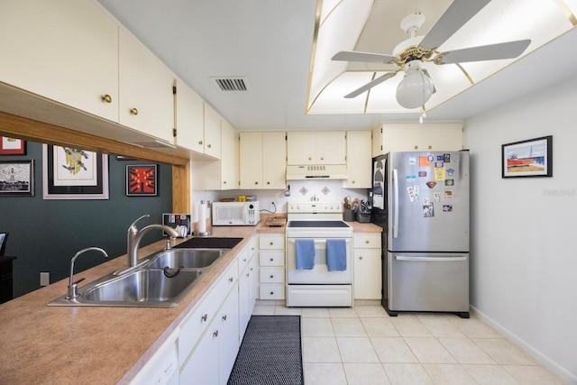 kitchen with white appliances, light tile patterned floors, visible vents, under cabinet range hood, and a sink