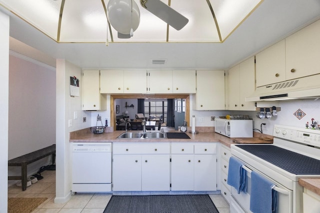 kitchen featuring light tile patterned floors, under cabinet range hood, white appliances, a sink, and backsplash