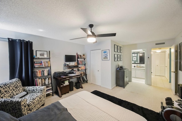 bedroom featuring light colored carpet, visible vents, ceiling fan, and a textured ceiling