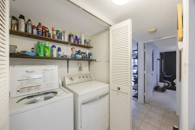 clothes washing area featuring a textured ceiling, laundry area, light tile patterned floors, and independent washer and dryer