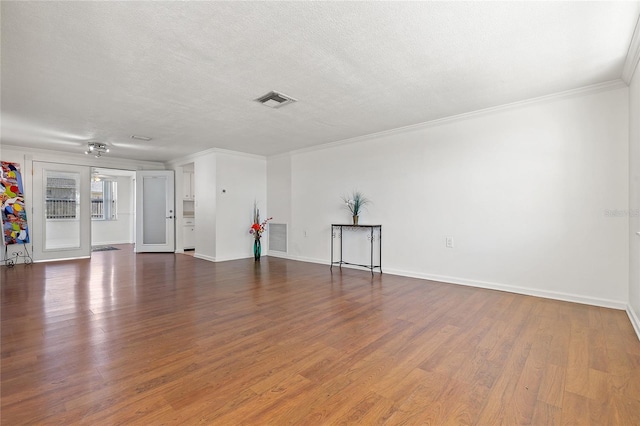 unfurnished living room with a textured ceiling, wood finished floors, visible vents, and crown molding