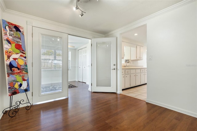 unfurnished room with light wood finished floors, baseboards, ornamental molding, and rail lighting