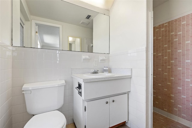 full bathroom with toilet, visible vents, tile walls, and vanity