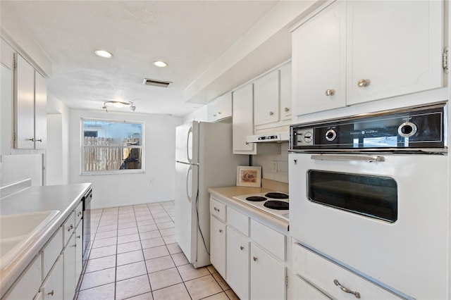 kitchen with white appliances, visible vents, and white cabinets