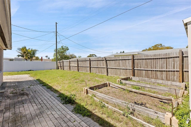 view of yard with a patio, a fenced backyard, and a garden