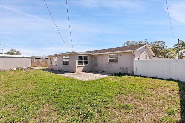 back of house with a yard, a patio area, a fenced backyard, and stucco siding