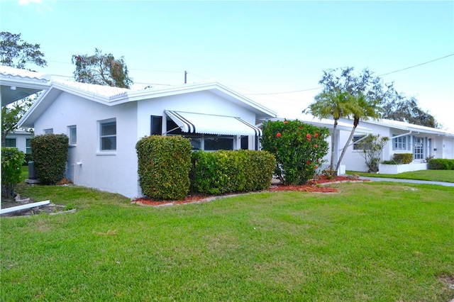 ranch-style house featuring a front yard and stucco siding