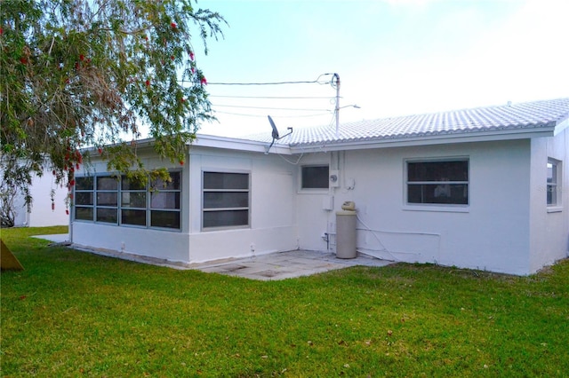 back of property featuring a lawn, a patio, and stucco siding