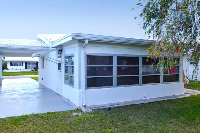 view of side of home with a lawn and stucco siding