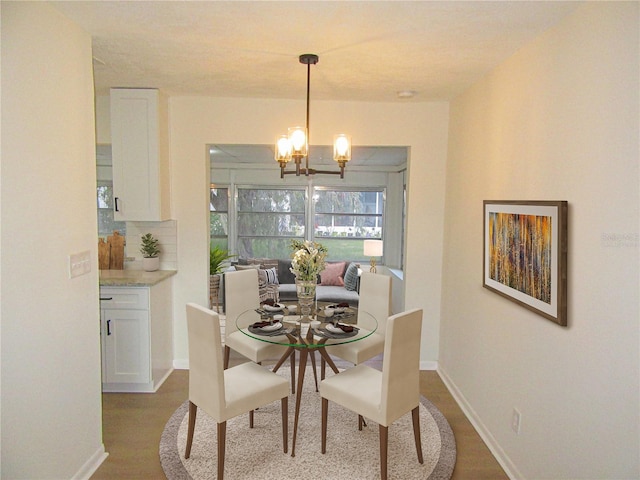 dining room featuring wood finished floors, baseboards, and an inviting chandelier