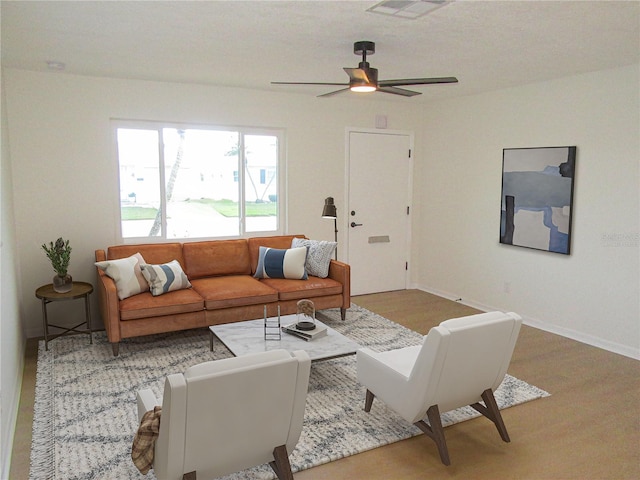 living room with visible vents, ceiling fan, baseboards, and wood finished floors