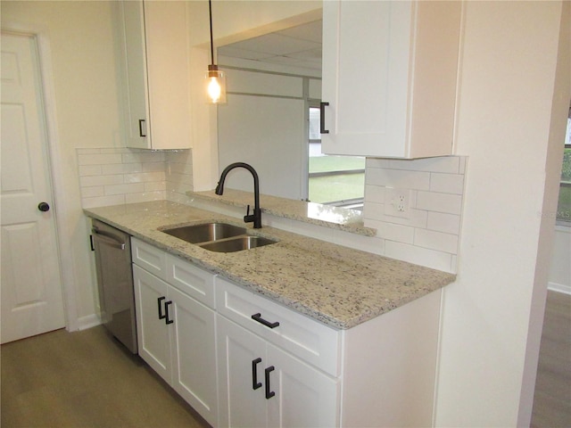 kitchen with a sink, white cabinets, stainless steel dishwasher, light stone countertops, and tasteful backsplash