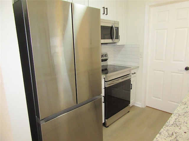 kitchen with stainless steel appliances, white cabinets, light wood-type flooring, backsplash, and light stone countertops