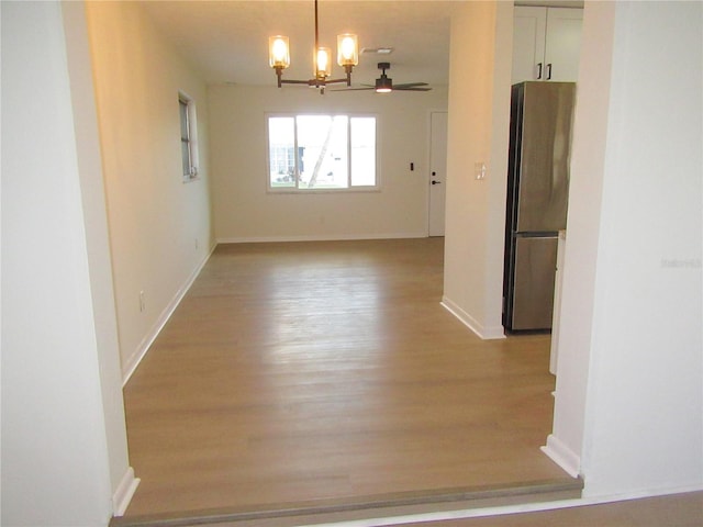 unfurnished dining area with light wood-style floors, baseboards, and a notable chandelier