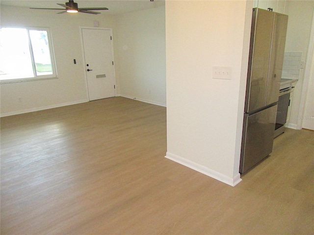 empty room featuring light wood-type flooring, baseboards, and a ceiling fan