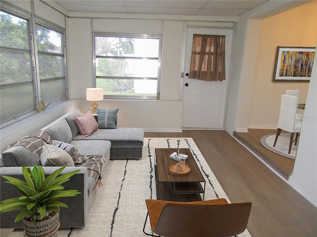 living room with a paneled ceiling, baseboards, and wood finished floors