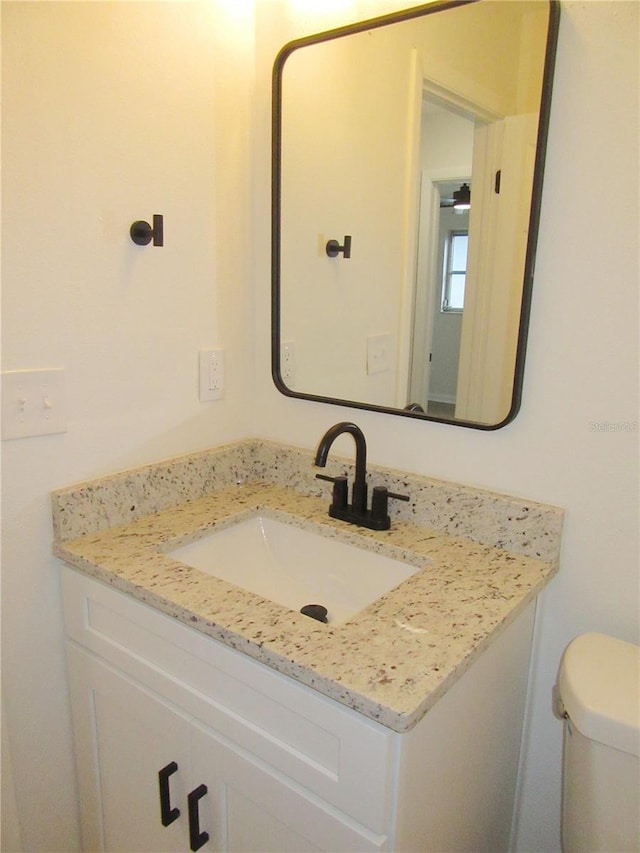 half bath featuring vanity and toilet