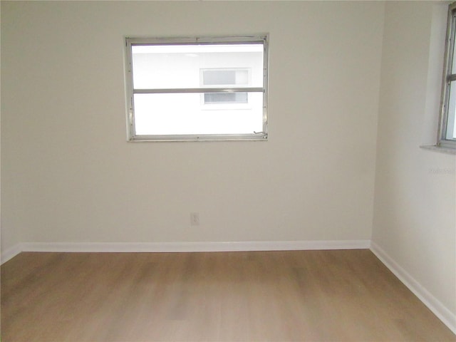 spare room featuring baseboards and wood finished floors